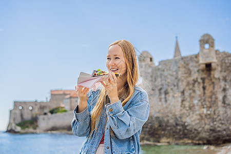 在古老的布德瓦镇旅游食用传统比萨饼的年轻妇女 前往黑山的概念 夏天 吃图片