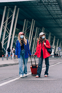 两个快乐的女孩在机场附近行走 带行李 空中旅行 暑假 牛仔裤 夏天图片