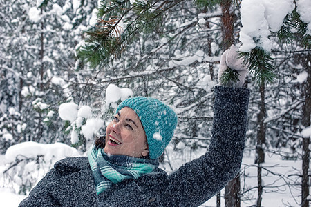 一个快乐的女孩 在冬天雪覆盖的森林里 抱着松树枝图片