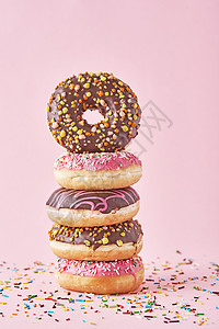 粉红色背景上装饰的多彩甜甜圈堆叠图片