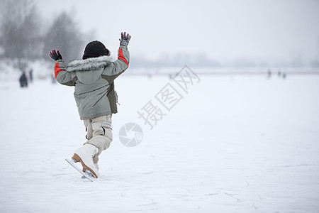 一个穿大溜冰鞋的小男孩 骑在湖边图片