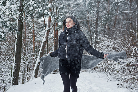 穿黑夹克的迷人女人的肖像 和冬季森林的灰色围巾 衣服 走图片