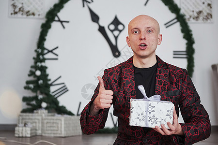 他身后有大钟的男人 穿着新年礼物盒和假日衣服坐着 还带着新年礼物箱背景图片