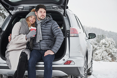 爱与家庭的概念 好情侣在冬天的乡村有周末 坐在现代汽车的后部 笑声  掌声 图片
