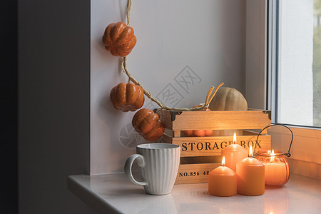 为万圣节准备你的家 一个木制南瓜盒 一个人造南瓜花环 橙色蜡烛 一杯茶和一个蜡烛灯笼装饰着窗户背景图片