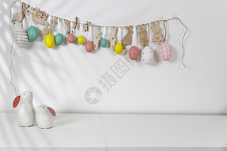 内部的片段 为复活节装饰的儿童房 墙上的塑料鸡蛋花环 桌子上的陶瓷兔子和木制立方体 您的文本的地方 复活节贺卡 装饰风格 斯堪的图片
