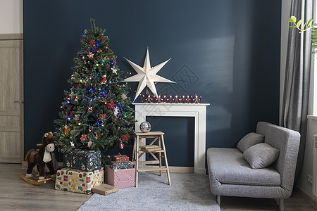 圣诞节前的家居装饰 装饰有花环灯的圣诞树 摇马 用精美纸包裹的礼物 带有大白纸星星和蜡烛的人造壁炉 手工制作的 装饰风格图片