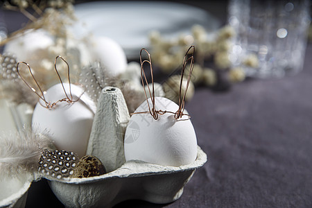 复活节概念 一个白蛋 有铜丝耳朵和在盒子里漆成的兔子睡脸 帕崔奇蛋和羽毛 午餐 餐具图片