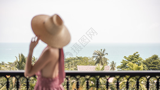 粉红色裙子和草帽女人的模糊侧面 站在酒店阳台上 海景图片