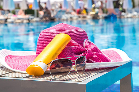 在酒店游泳池旁边的 一瓶太阳霜 帽子和墨镜 阳光 配件图片