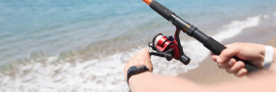 男子在海滨近岸密闭上用棍子捕鱼图片