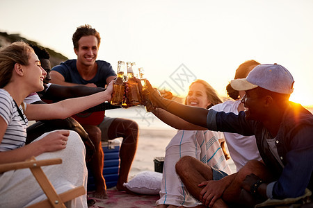 为成为家人的朋友干杯 一群朋友在沙滩上喝着饮料被拍到的镜头图片