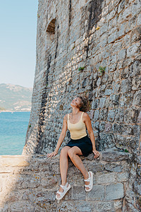 坐在石墙上的漂亮女孩 背景是蓝海 黑山的布德瓦 女性 快乐的图片