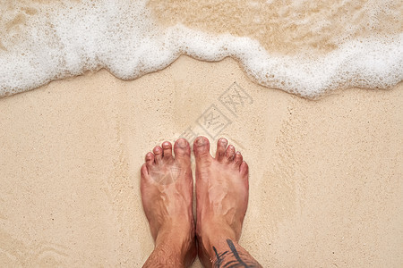 盐色头发和沙脚趾 海边一双男人脚的高角度拍摄图片