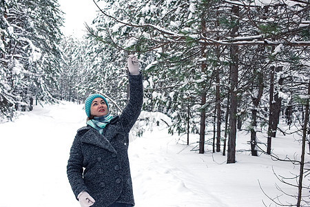 一位在冬季雪覆盖的森林中快乐的女士 拿着松树枝图片