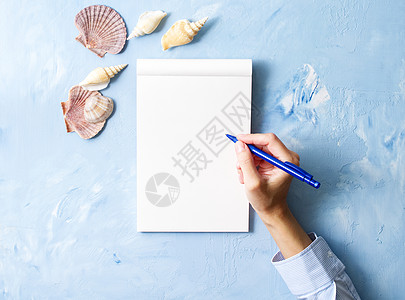 女人用笔记本写在石蓝桌子上 用贝壳的壁架装饰 顶层风景图片