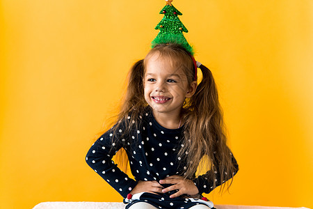 令人惊讶的快乐的小女学生圣诞树装饰 头领圆点服装展示橙色背景的拇指 新年 节日 庆典 冬季概念等都值得一提 竖起大拇指 橙子图片