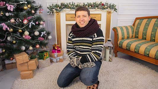 一个年轻人坐在他家的地板上 圣诞主题图片