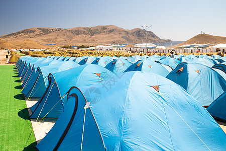 在温暖海滨一个简易节日镇热海沿岸与大量旅游帐篷一起露营 宿营人数众多的旅游帐篷图片