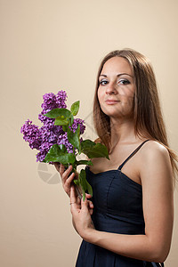 美丽的年轻女孩穿着黑色的裙子 带着一束薄饼花 紫色 礼物图片