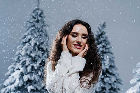 新年庆祝活动 快乐的女孩与飘落的雪花 年轻女子穿着温暖的白色套头衫和白色袜子 在下雪天的寒假 森林 冬天图片