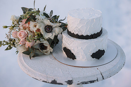 黑白设计蛋糕 站在雪上冬季森林的一个摊子上 附近有一束婚礼花束在旁边 冻结的 桌子图片