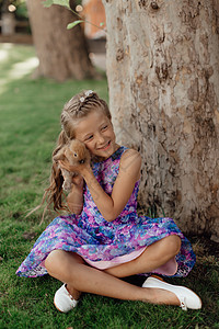 小姑娘和兔子坐在绿草地上 复活节那天 可爱的小女孩拿着兔子在她手里 春天 阳光图片