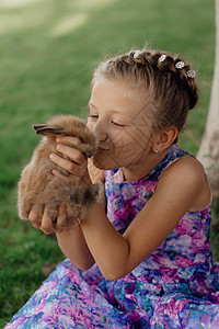 小姑娘和兔子坐在绿草地上 复活节那天 可爱的小女孩拿着兔子在她手里 动物 兔子耳朵图片