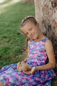 小姑娘和兔子坐在绿草地上 复活节那天 可爱的小女孩拿着兔子在她手里 动物 幸福图片