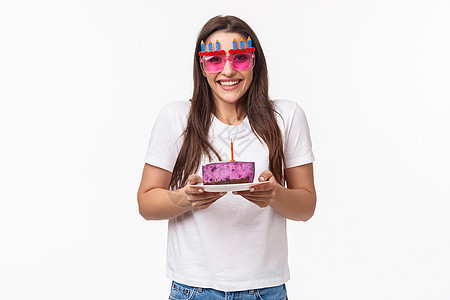 娱乐 乐趣和假期的概念 为纪念她而举办派对 庆祝生日 戴着滑稽的狂欢节眼镜 拿着带蜡烛的生日蛋糕 微笑的相机快乐 白色背景的女孩图片