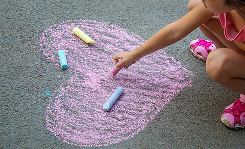 儿童用粉笔在沥青上画了一颗心 家庭 假期 艺术图片