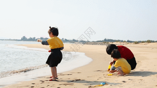 在海边的女孩妈妈带孩子在海边玩沙子GIF高清图片