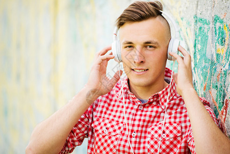 留着现代发型的年轻人戴着耳机听音乐图片