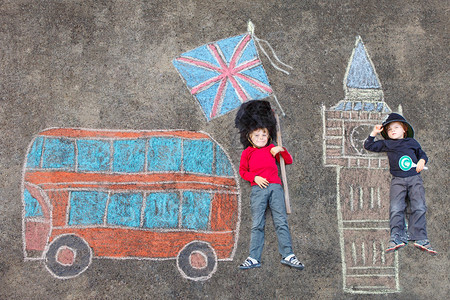 两个穿着英国女王卫队士兵和制服的滑稽小男孩玩着用彩色粉笔画的伦敦画有大本钟英国图片