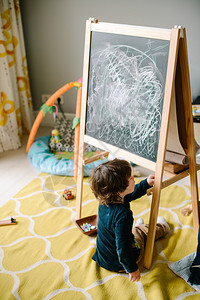 小男孩坐在地板上在黑板上画粉笔家庭图片