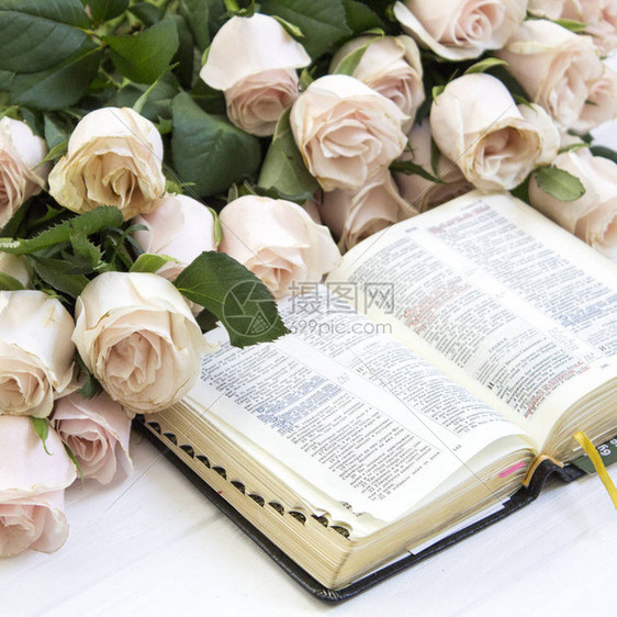 美丽的玫瑰和木制背景上的圣经图片