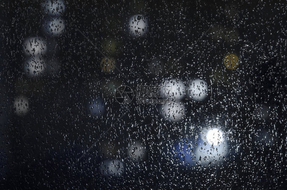 雨滴在夜景背下的窗户上带有散焦灯的情感忧郁抽象背景由于景深较浅图片