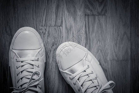 一双运动风格的灰色时尚鞋紧贴在空桌球地板的抽象背景上图片