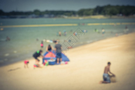 抽象模糊的人在湖边的白沙滩上享受户外活动美国德克萨斯州大草原城滨水林恩溪公园家人搭帐篷图片
