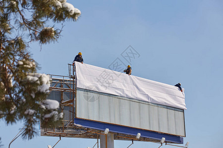 工人准备广告牌以安装新广告在梯子上工作的工业登山者图片