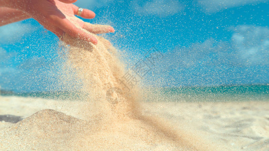 夏天的风将沙子从女孩的手中吹散图片