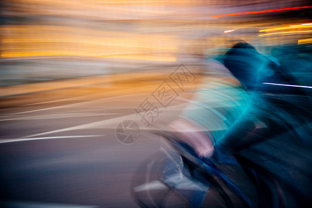 对通过移动应用程序运送食物的快速骑自行车者环光灯柱抽象地分散焦图片