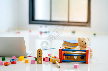 各种玩具和娃被放在玻璃窗前笔记本电脑旁边的地板上图片