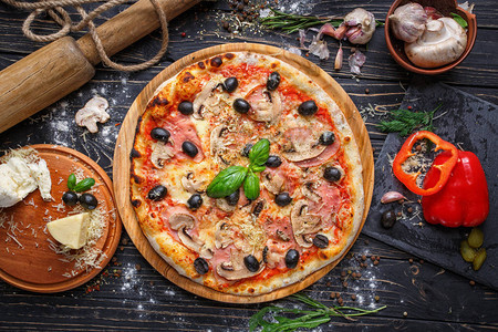 精致的比萨配火腿蘑菇和橄榄餐馆或比萨店的海报香料中黑色木质背图片