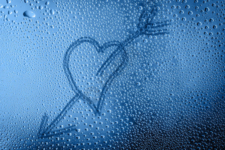 手绘心被箭刺穿的心和蓝色玻璃上的水滴图片
