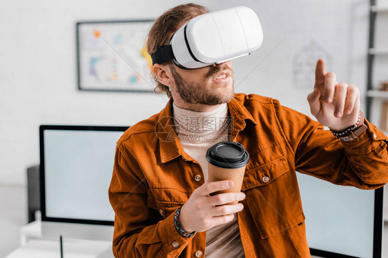 3位艺术家在虚拟现实头盔中拿着咖啡用手图片
