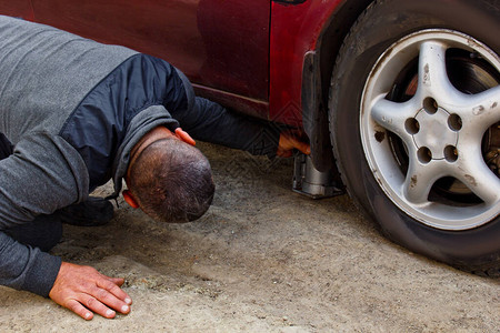 汽车修理工用电动螺丝刀在外面换轮胎汽车服务手更换车轮上的轮胎图片