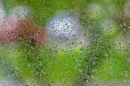 在阳台窗户玻璃窗玻璃后面的雨滴和风景的抽象背景图片