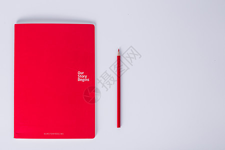 白色背景下红本子和红色铅笔摆拍图片