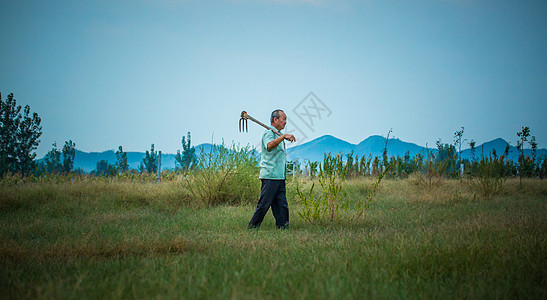 种地清晨农夫扛着锄头在山下开荒种植背景